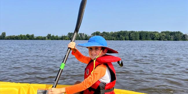 Young boy paddling a yellow kayak