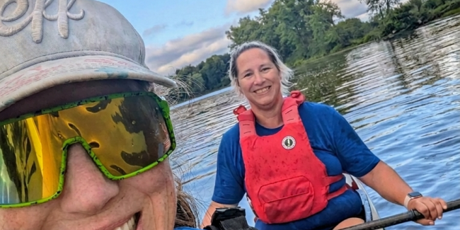 Two women smiling in a double sprint kayak on the river