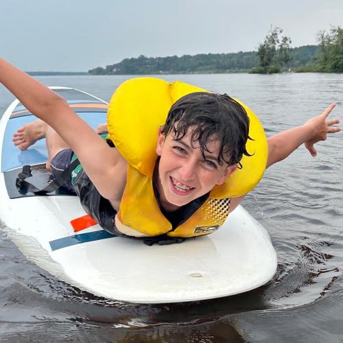 Smiling boy on his belly, floating on a stand up paddleboard